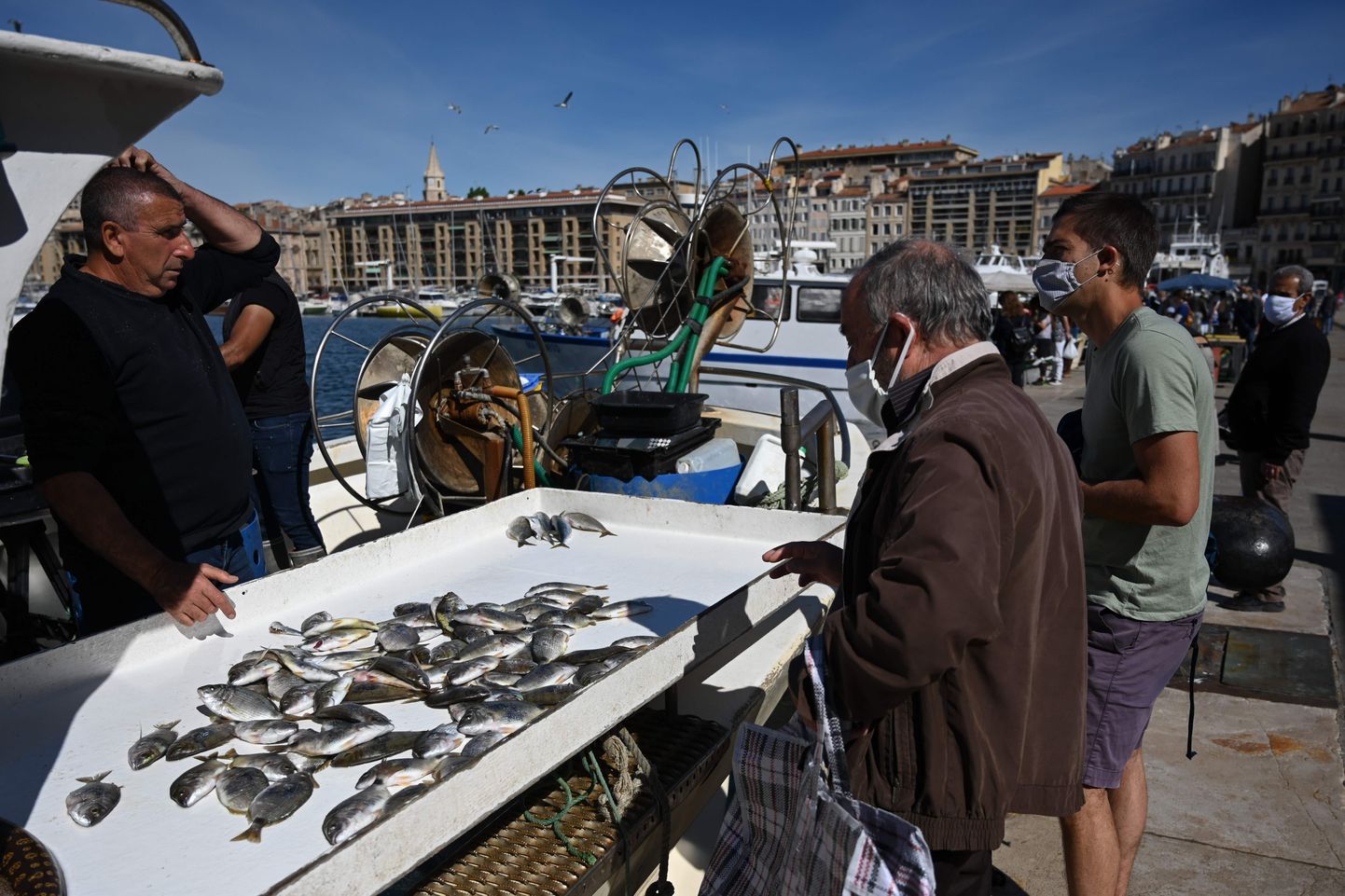 Näomaskis inimesed ostmas värsket saaki otse kalameestelt Marseille'i Vieux Porti sadamas.