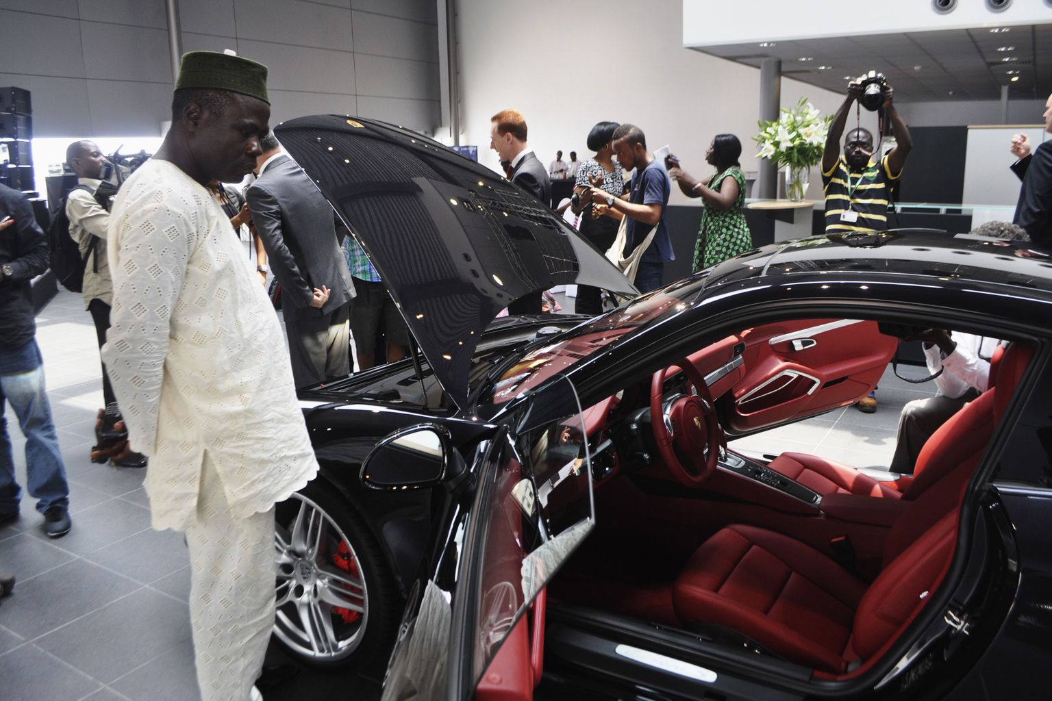Nigeeria noored ja jõukad Lagoses avatud Porsche esindussalongis autosid uurimas.