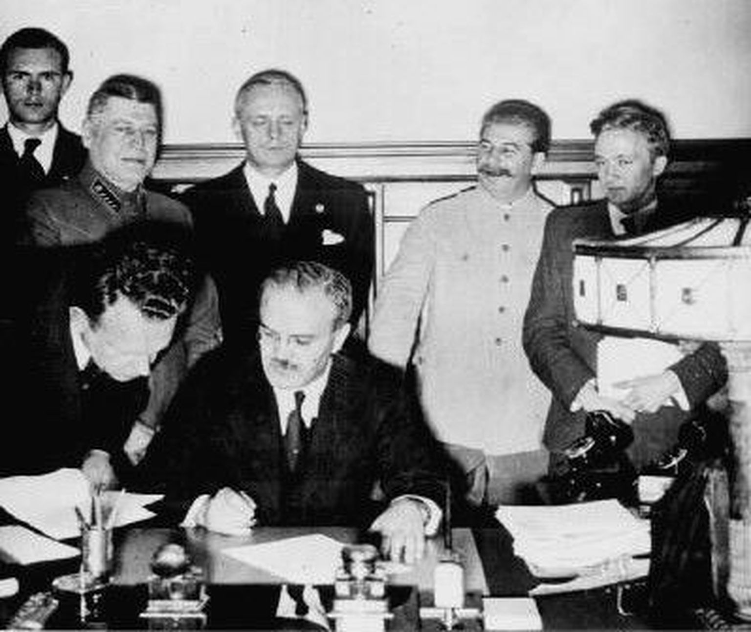 Molotovi-Ribbentropi pakti allkirjastamine 23. augustil 1939. Molotov istub ees keskel, Ribbentrop seisab tema selja taga.