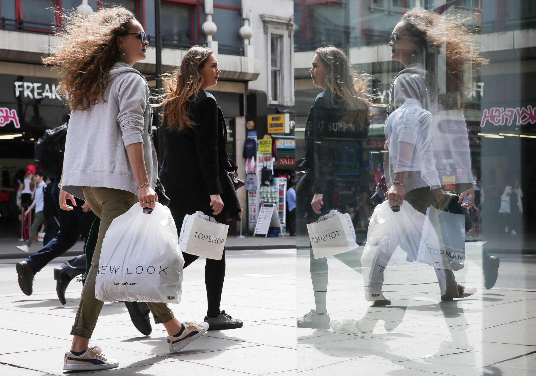 Jalakäijad peegeldumas Londonis Oxford streetil asuva ostukeskuse klaasseinal.