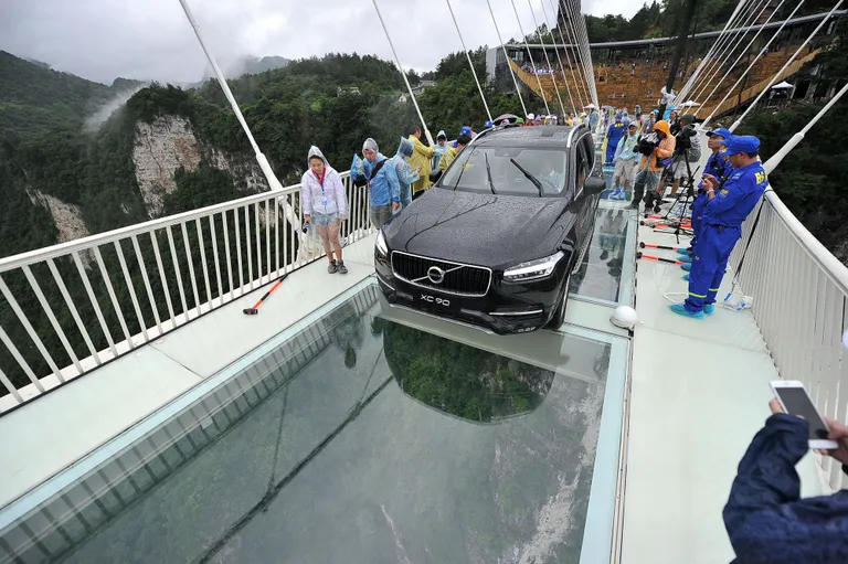 A car filled with passengers drives across a glass-bottomed suspension bridge in Zhangjiajie in southern China's Hunan province Saturday, June 25, 2016. The 430-meter (1,410-foot) bridge stretches about 300 meters (984 feet) above a valley in a scenic zone, and officials partially smashed the glass surface on Saturday as part of a demonstration of the bridge's safety. (Chinatopix via AP) CHINA OUT