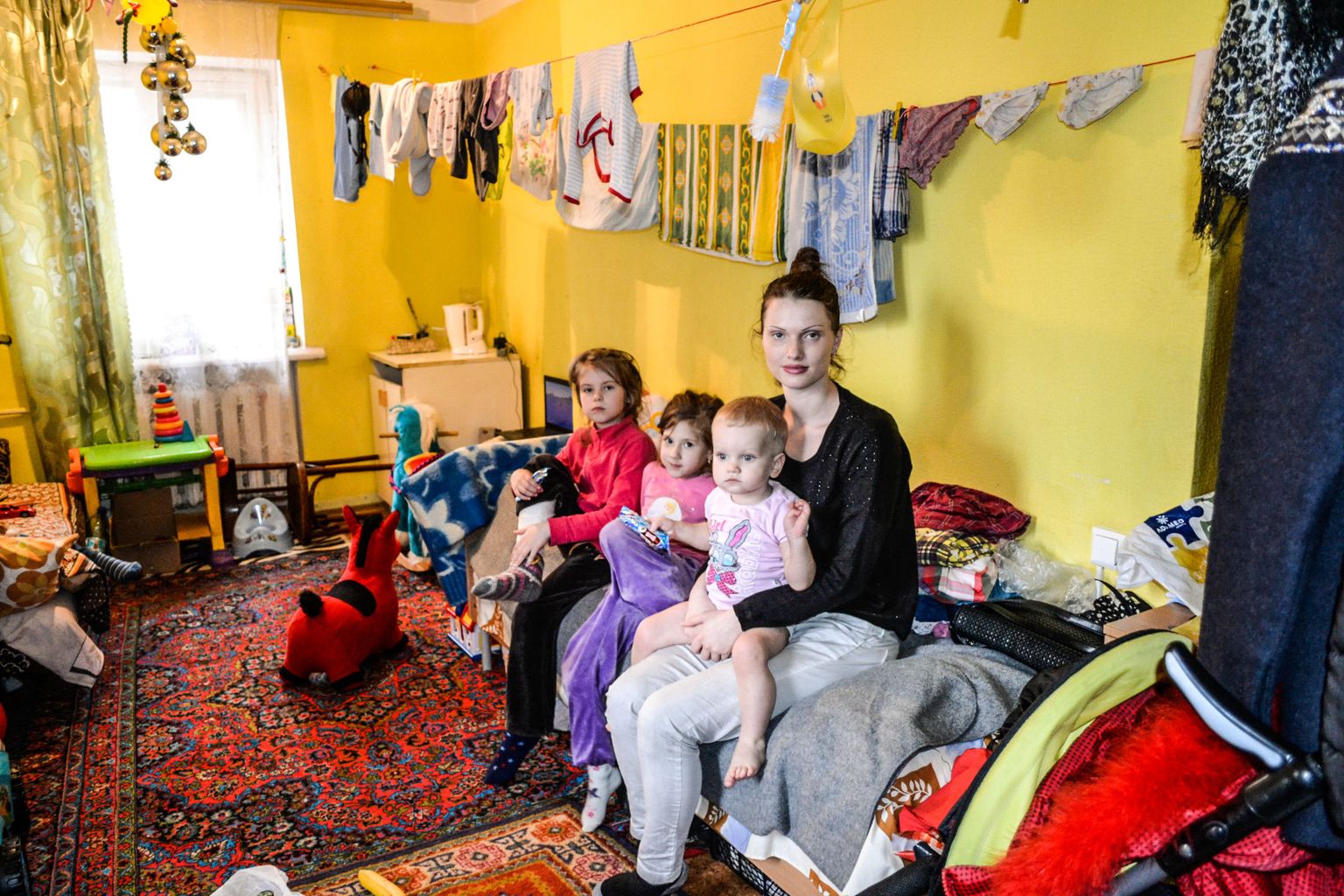 Ühiselamutoa voodil istub Donetski oblastist pärit Katja Tsupova koos aastase poja Glebi ning tüdrukutega, kellest keskmine on haiglas viibiva Marina tütar Mariam.