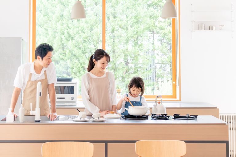 Японская семья на кухне. Ребенок участвует в процессе готовки еды. Иллюстративное фото.
