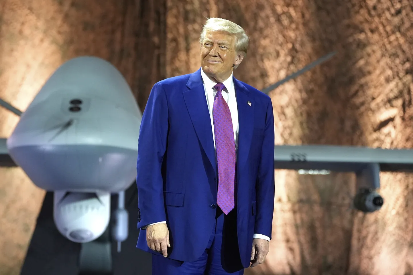 ASV prezidents Donalds Tramps pirms uzrunas militārajam personālam Al Udeida gaisa spēku bāzē, 2025. gada 15. maijā, Dohā, Katarā. Viņam aiz muguras redzams drons MQ-9 Reaper.