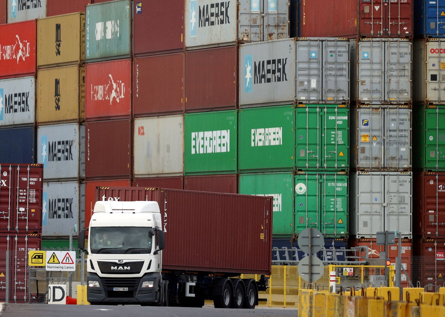 FILE PHOTO: A truck drives past stacked shipping containers at the port of Felixstowe, Britain, October 13, 2021. REUTERS/Hannah McKay/File Photo