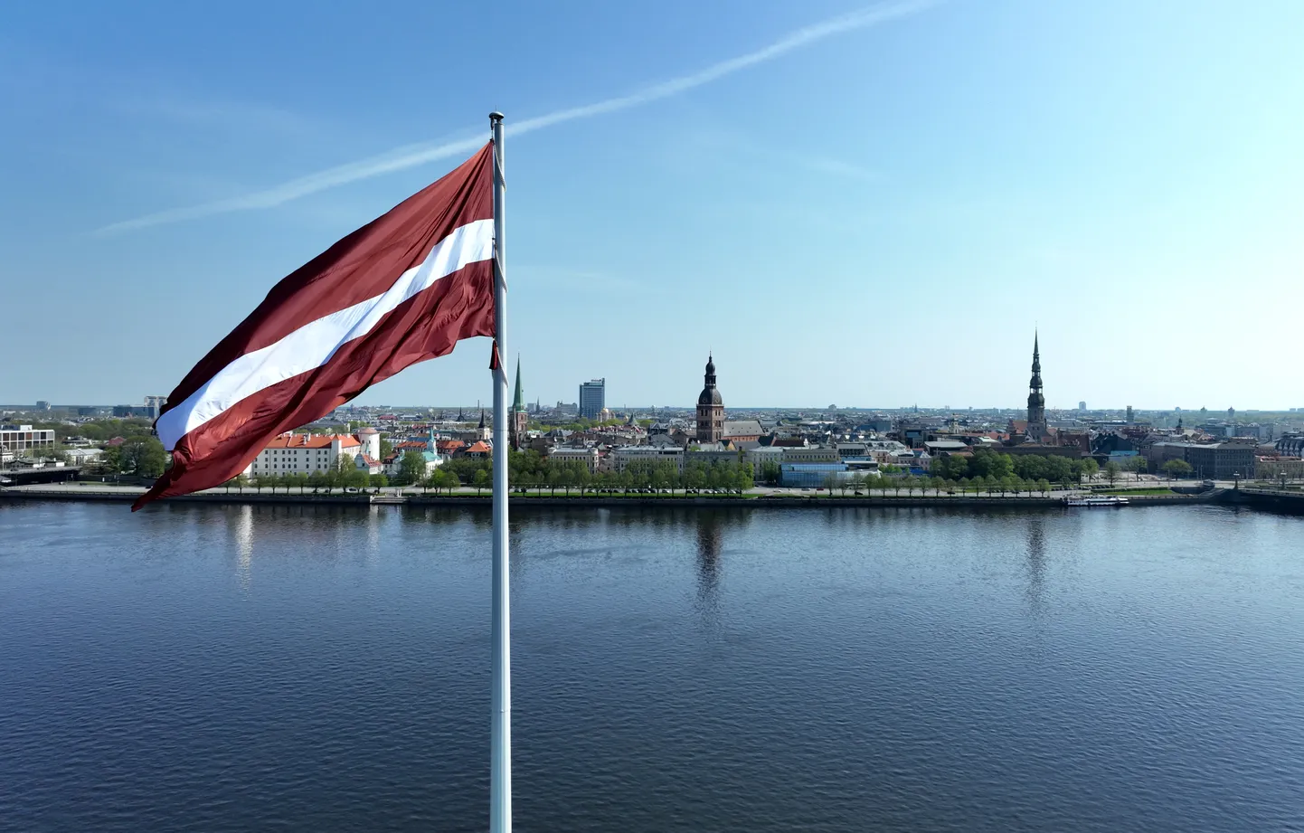 Latvijas karogs uz AB da,bja un Rīgas panorāma.