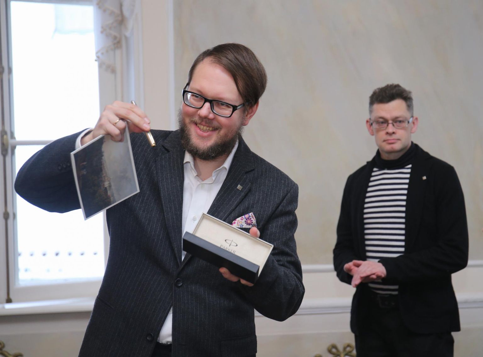 2019. aasta linnakirjanik Vahur Afanasjev võttis eile suure rõõmuga vastu õnnitlusi, eriti Tartu linnapea Urmas Klaasi kingituse – sulepea. Taustal žürii liige Berk Vaher.