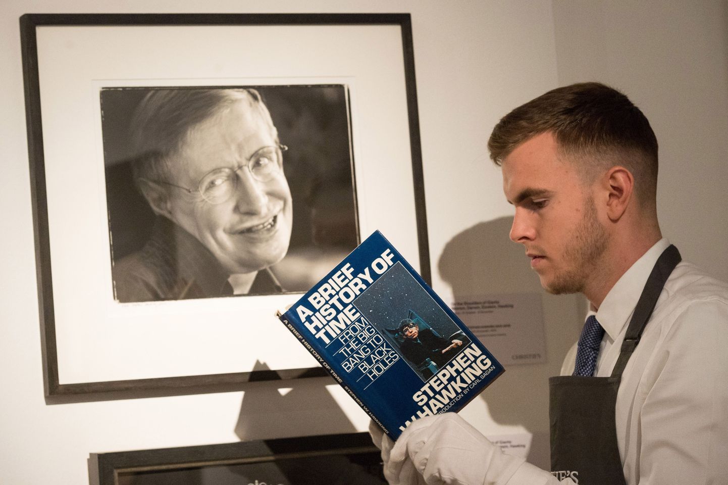 Oksjonimaja Christie's töötaja hoiab käes Stephen Hawkingi raamatut.