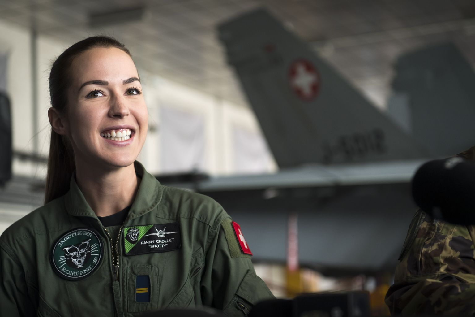 Fanny Chollet on esimene naine, kelle kätte on Šveitsi õhuväes usaldatud hävitaja juhtimine. Tema töövahendiks on taustalt paistev F/A-18 Hornet ning kodubaasiks Payerne, kus täna noort hävituslendurit ajakirjandusele tutvustati.