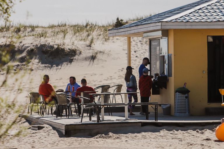Солнечный день привлек людей на пляж. Прибрежные кафе и пункты проката делают последние приготовления к летнему сезону.