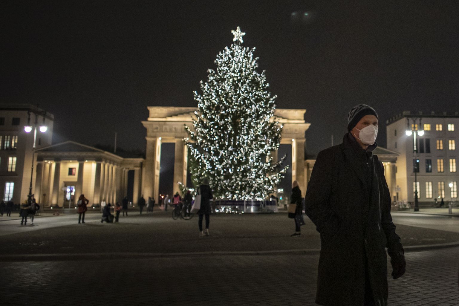 Saksamaa valitsus kavandab uusi piiranguid, mis võivad jõustuda 28. detsembril. Pildil inimesed Berliinis Brandenburgi värava ees asuva jõulukuuse ümber.