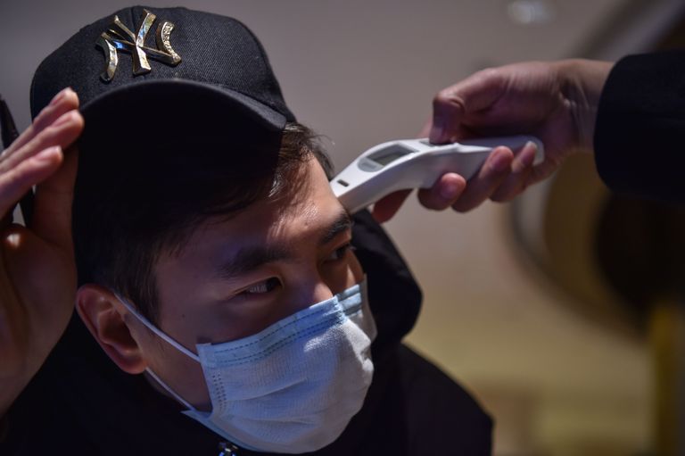 Ühe Wuhani hotelli töötaja mõõtmas äsja asutusse saabunud kliendi kehatemperatuuri.