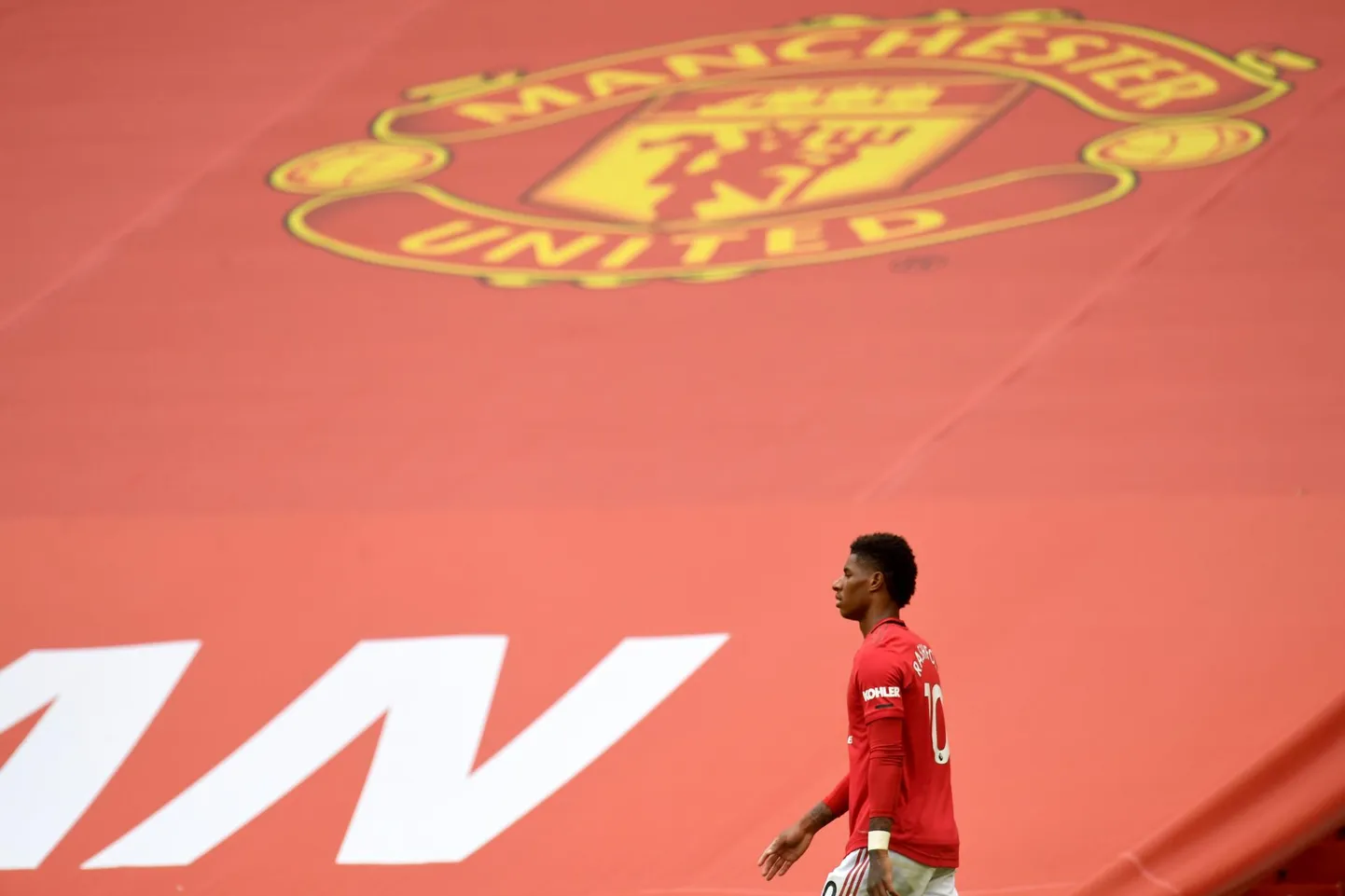 Manchester Unitedi jalgpallur Marcus Rashford kõnnib Old Traffordil mitte publiku, vaid suure bänneri ees.
