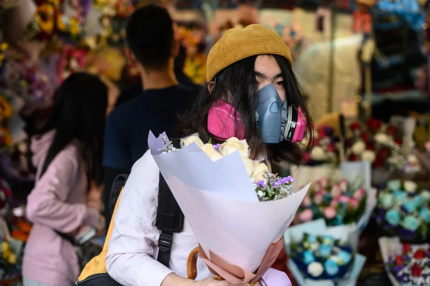 Respiraatoriga end viiruse Covid-19 eest kaitsev mees ostmas valentinipäeval lilli Hongkongis. 