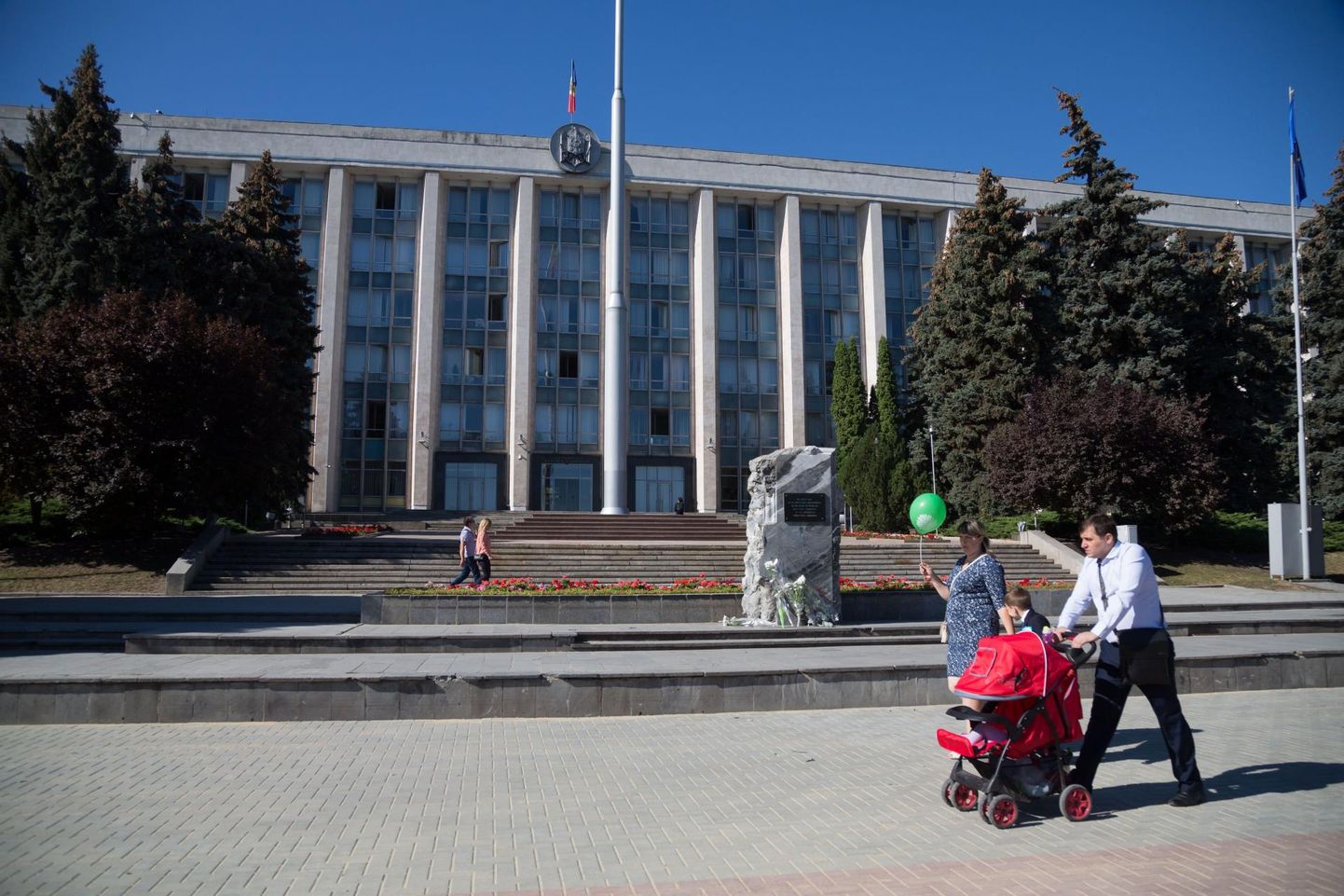 Perekond jalutab Moldova pealinnas Chișinăus valitsushoone ees.