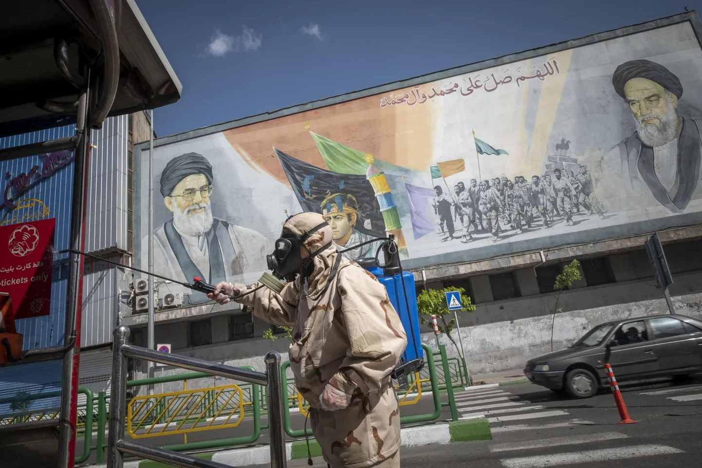 Islami revolutsioonilise kaardiväe liige desinfitseerib bussipeatust, mille taustal seinamaaling endise ajatolla Ruhollah Khomeini (paremal) ja Iraani praeguse juhi ajatolla Ali Khamenei piltidega.